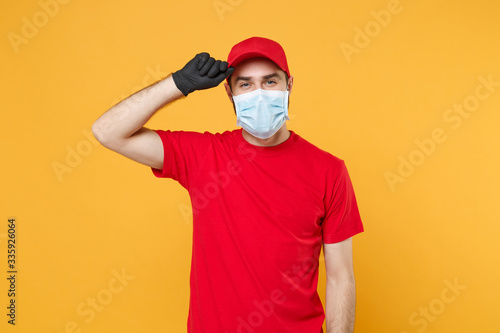 Delivery man in red cap blank t-shirt uniform sterile face mask gloves isolated on yellow background studio Guy employee working courier Service quarantine pandemic coronavirus virus 2019-ncov concept