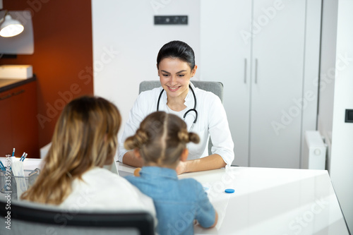 Caucasian mother with her little daughter talking to doctor indoors