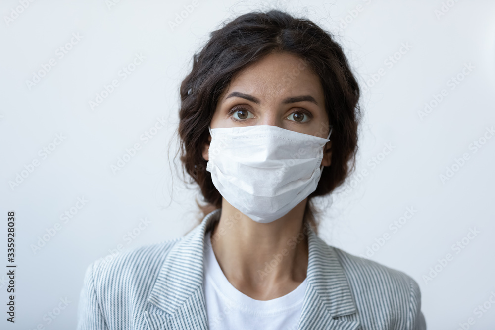 Head shot portrait of worrying young brunette woman covering nose and mouth with respiratory protective medical equipment. Stressed lady wearing facial mask, stop virus contagion, healthcare concept. Head shot portrait of worrying young brunette woman covering nose and mouth with respiratory protective medical equipment. Stressed lady wearing facial mask, stop virus contagion, healthcare concept.