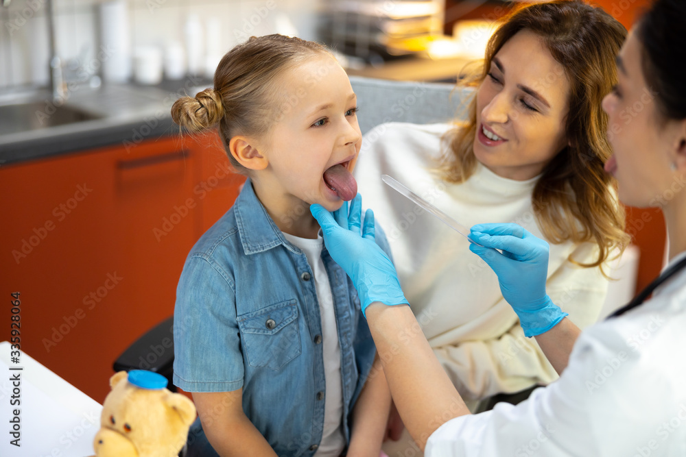 Caucasian female doctor in rubber gloves examines small patient Caucasian female doctor in rubber gloves examines small patient
