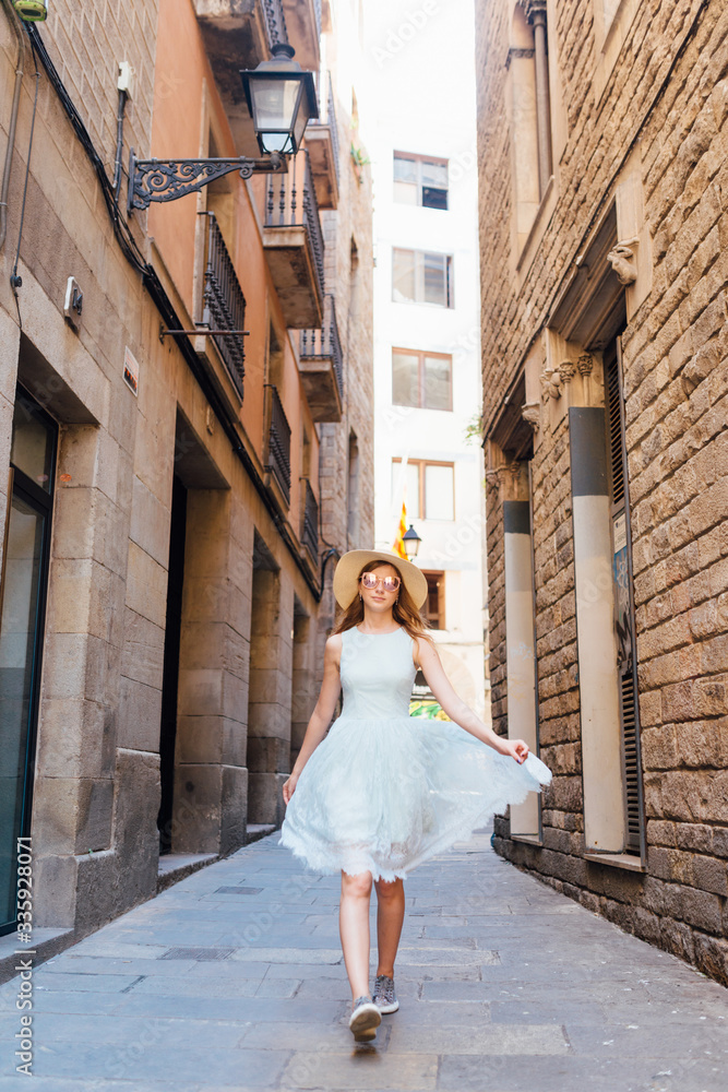 A young girl in a blue dress walks through the city of Barcelona