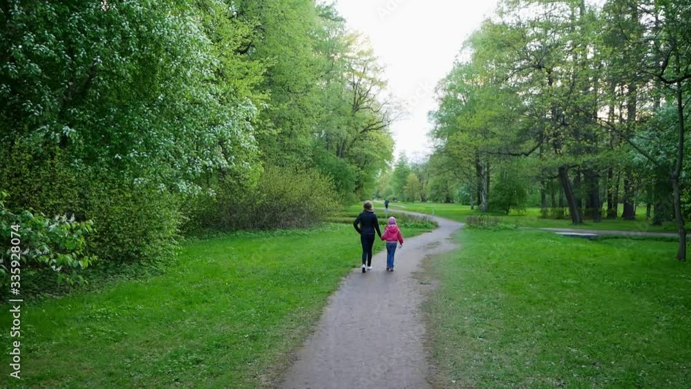 A young girl and a girl walk through the Park holding hands. Around them blooming cherry trees.Tulip Festival on Yelagin Island Of the Park of Culture and Recreation in may in St. Petersburg. A young girl and a girl walk through the Park holding hands. Around them blooming cherry trees.Tulip Festival on Yelagin Island Of the Park of Culture and Recreation in may in St. Petersburg.