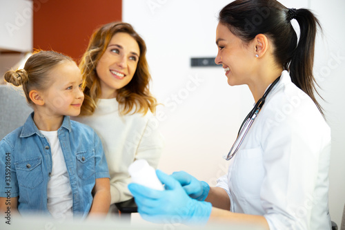Little kid sitting on knees of her mother and listening to doctor
