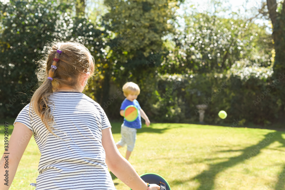 Children playing outside a brother and sister play a ball game in a garden Children playing outside a brother and sister play a ball game in a garden