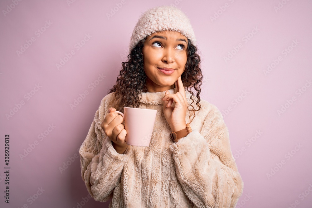 Young beautiful woman with curly hair drinking mug of coffee over isolated pink background serious face thinking about question, very confused idea Young beautiful woman with curly hair drinking mug of coffee over isolated pink background serious face thinking about question, very confused idea
