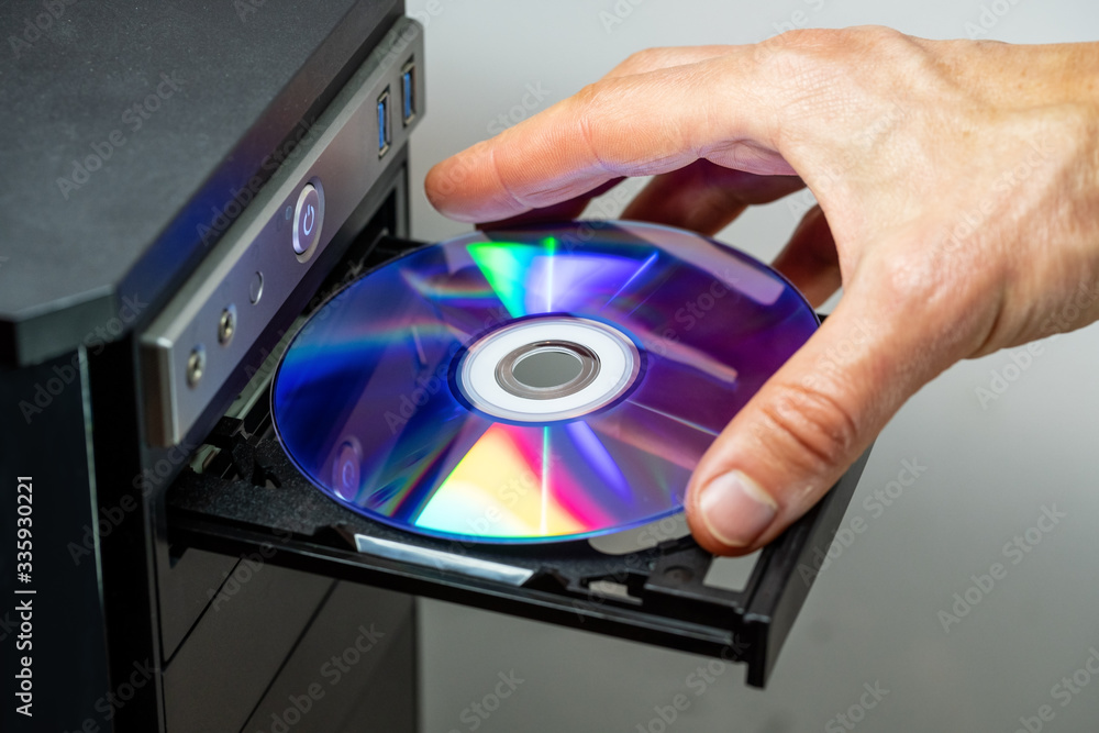 Hand inserting DVD into a computer. Closeup. Hand inserting DVD into a computer. Closeup.