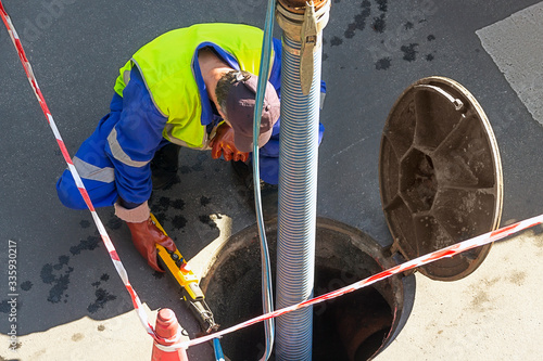Fotografija sewerage truck service and utility workers for cleaning sewer pipes in city stre
