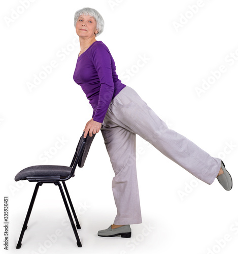 Happy charming beautiful elderly woman doing exercises at home on a chair. Workout gymnastics for health. On a white background