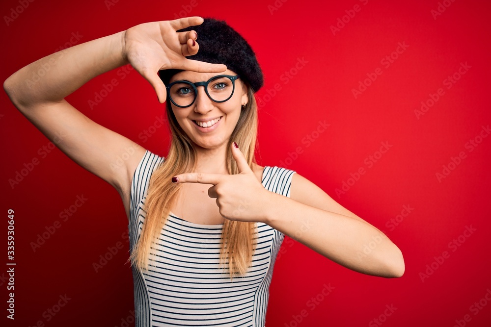Beautiful blonde woman with blue eyes wearing french beret and glasses over red background smiling making frame with hands and fingers with happy face. Creativity and photography concept. Beautiful blonde woman with blue eyes wearing french beret and glasses over red background smiling making frame with hands and fingers with happy face. Creativity and photography concept.