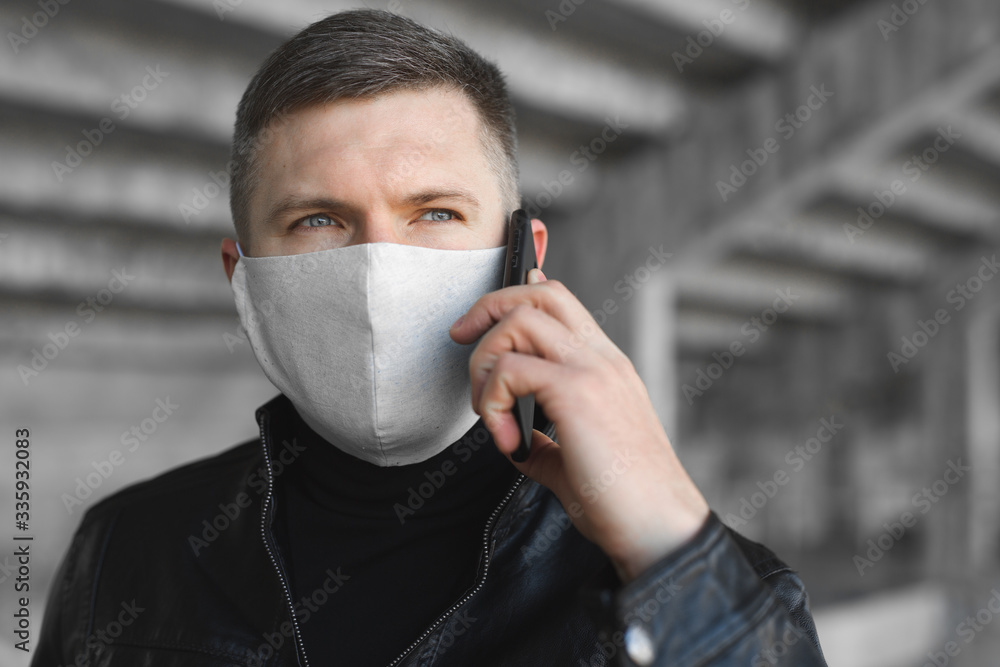 Young man with a medical face mask and a phone in the hands at the street. Air pollution coronavirus protection concept. Covid 19