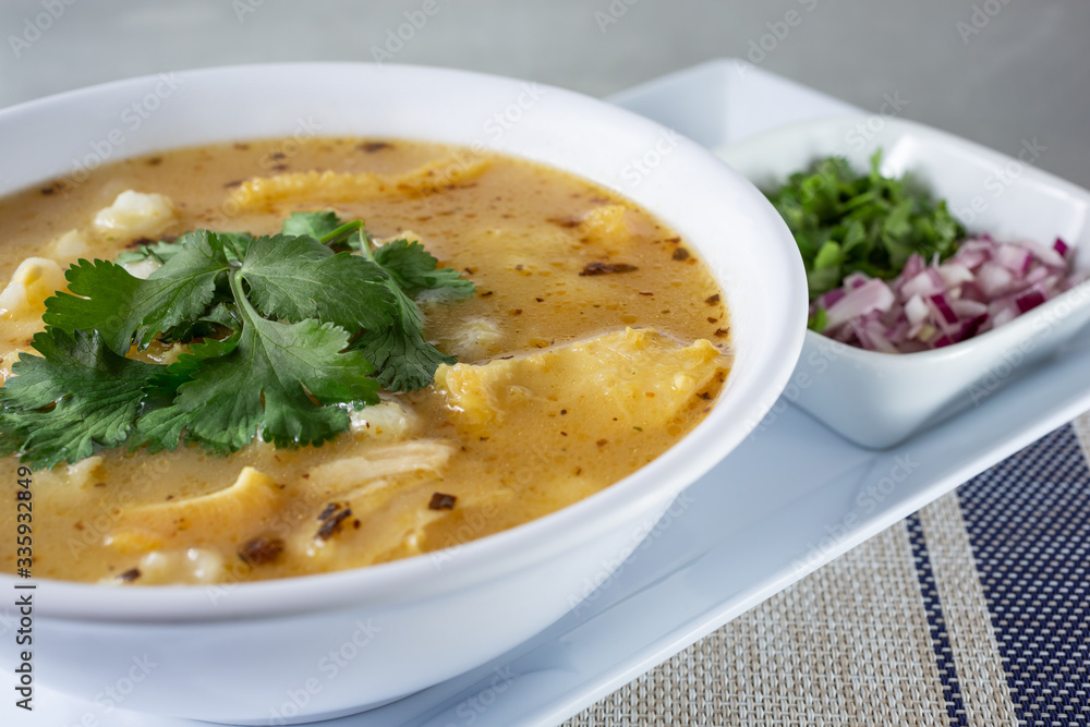 A view of a bowl of Mexican menudo soup, in a restaurant or kitchen setting.