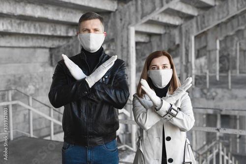 A masked man and woman show a stop sign for the coronavirus. The 2020 pandemic covid19. Stop the coronavirus. Quarantine. Coronavirus vaccine
