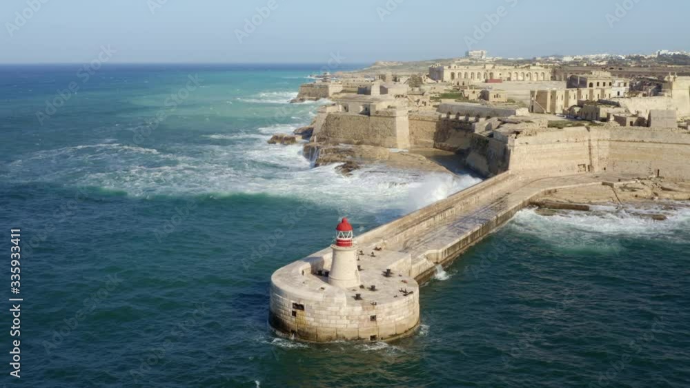 Aerial top view of red lighthouse, fort Ricasoli. Big waves in mediterranean sea. Grand harbor. Malta country Aerial top view of red lighthouse, fort Ricasoli. Big waves in mediterranean sea. Grand harbor. Malta country