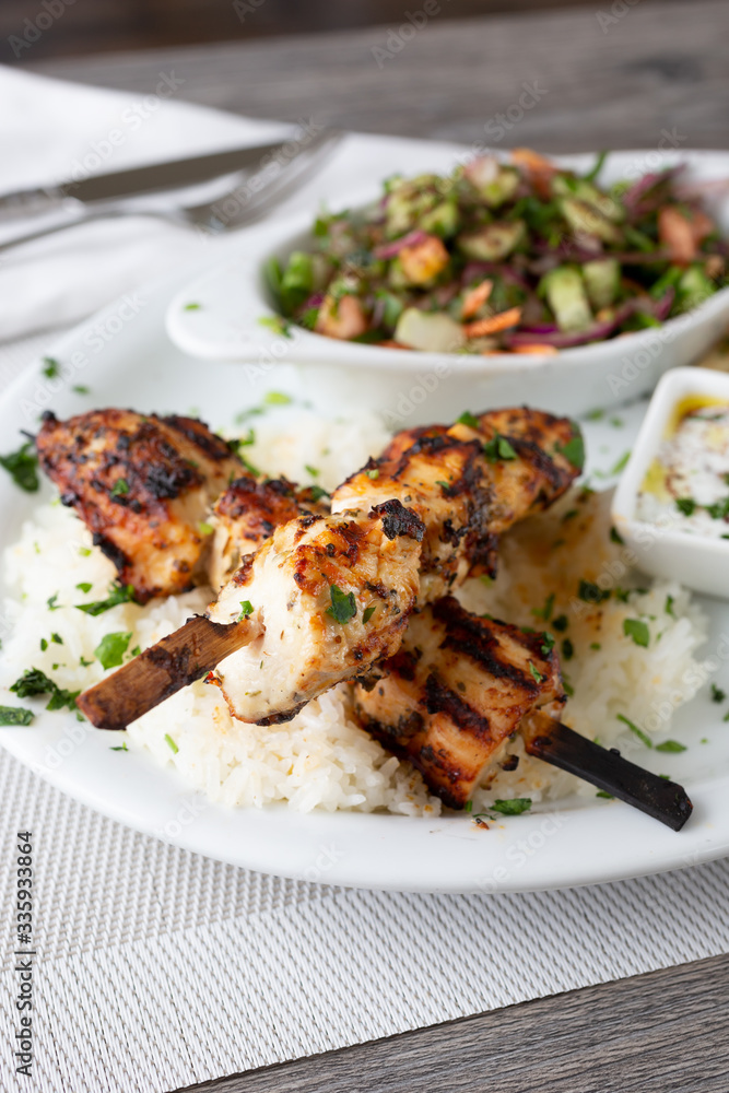 A view of a Mediterranean plate of chicken kabob, in a restaurant or kitchen setting.