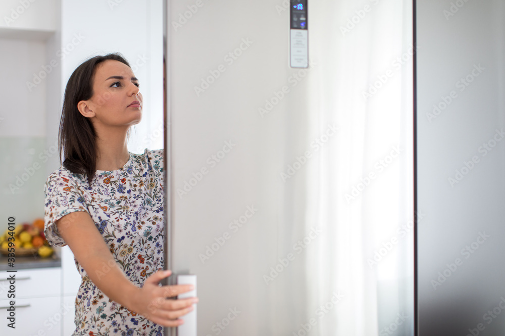 Pretty, young woman in her modern kitchen, by the fridge, about to cook a healthy meel for her family (color toned image) Pretty, young woman in her modern kitchen, by the fridge, about to cook a healthy meel for her family (color toned image)