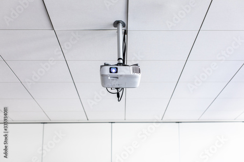 A white overhead projector on ceiling in a conference room/modern classroom (color toned image)