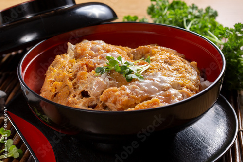A view of a bowl of Japanese chicken katsu don, in a restaurant or kitchen setting.