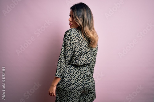 Young beautiful woman wearing fashion urban clothes, model wearing casual street style standing over pink background