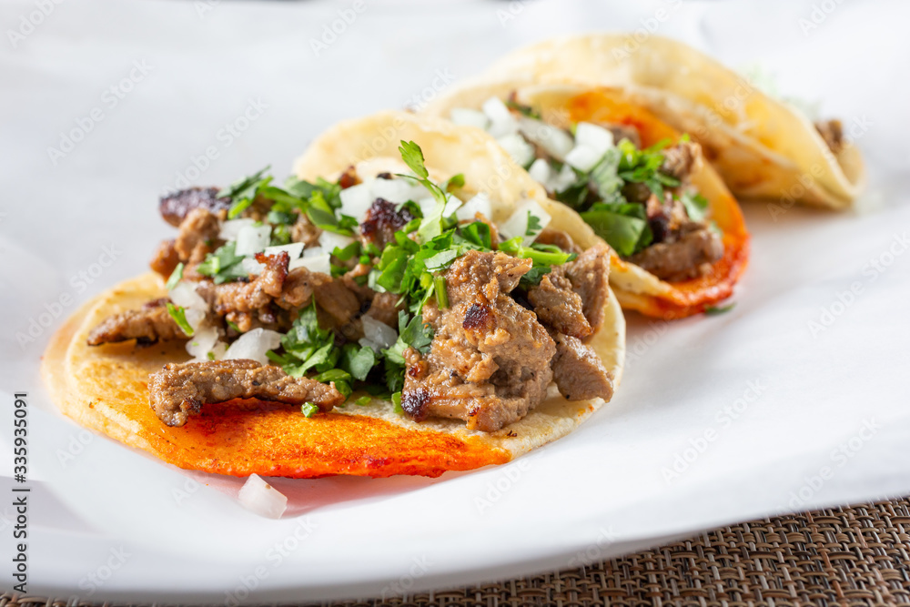 A closeup view of several street tacos, in a restaurant or kitchen setting. A closeup view of several street tacos, in a restaurant or kitchen setting.