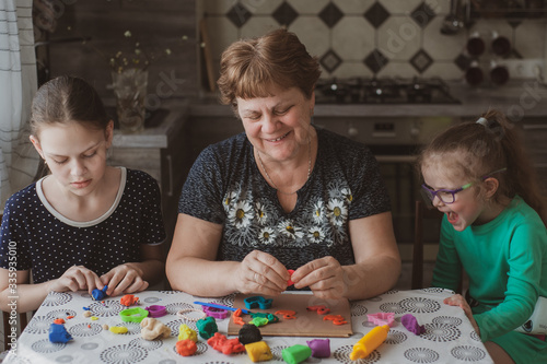 Foto An adult woman and two little girls make plasticine figurines at home