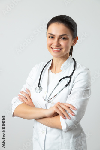 Cute smiling doctor posing for camera against light background