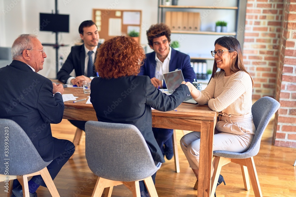 Group of business workers smiling happy and confident in a meeting. Speaking with smile on face working together shaking hands for agreement at the office.