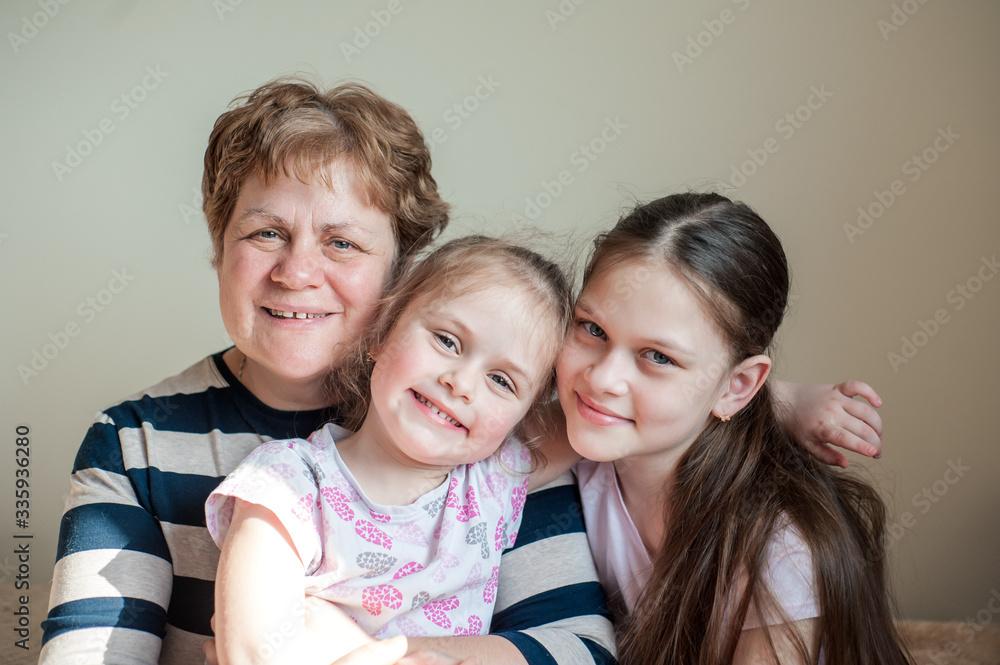 Closeup portrait of a happy grandmother and her granddaughters inside. The concept of family values. Closeup portrait of a happy grandmother and her granddaughters inside. The concept of family values.