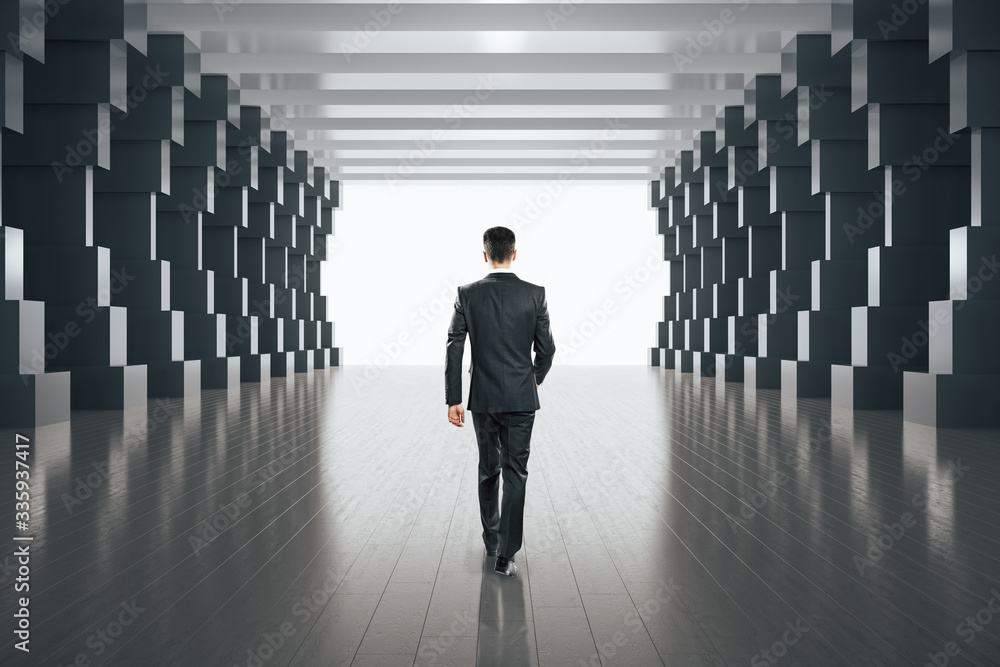 Fototapeta premium Businessman walking in minimalistic concrete tunnel interior.