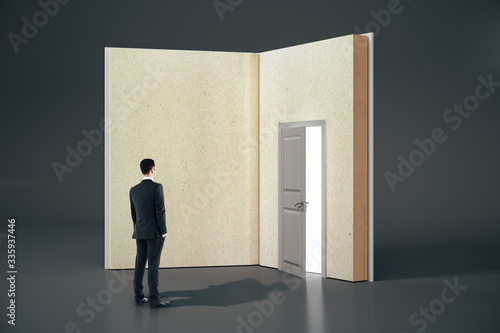 Businessman looking at abstract open book with door on gray background. © Who is Danny