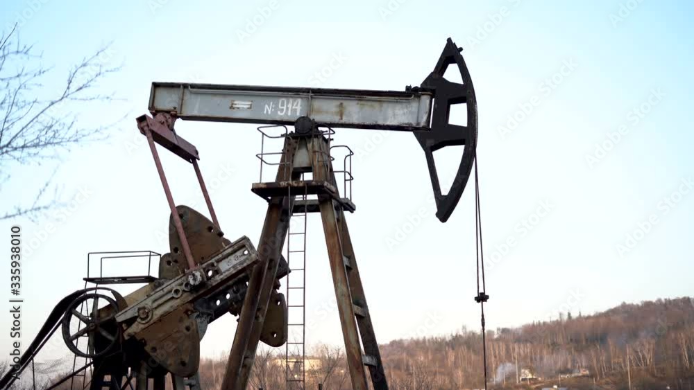 Old Oil Well Pump Jack Extracting Petroleum. Working Oil Pump Jack Against The Sky. Extraction of Petroleum. Fossil Fuel Energy. Old Oil Well Pump Jack Extracting Petroleum. Working Oil Pump Jack Against The Sky. Extraction of Petroleum. Fossil Fuel Energy.