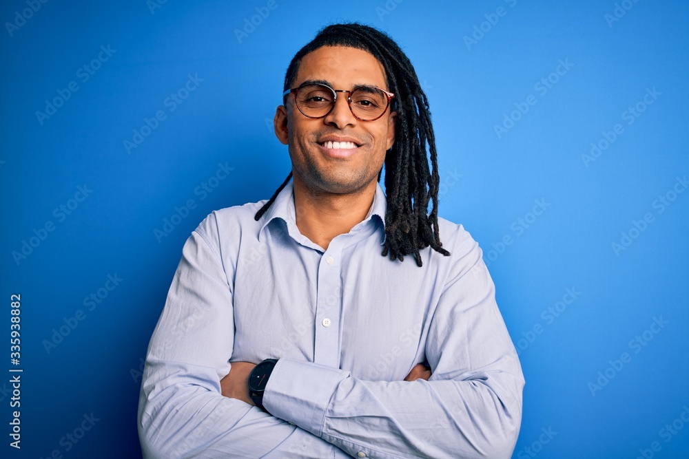 Young handsome african american man with dreadlocks wearing casual shirt and glasses happy face smiling with crossed arms looking at the camera. Positive person. Young handsome african american man with dreadlocks wearing casual shirt and glasses happy face smiling with crossed arms looking at the camera. Positive person.