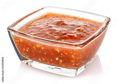 Hot tomato sauce with spices and salt in a small transparent glass square bowl isolated on white background