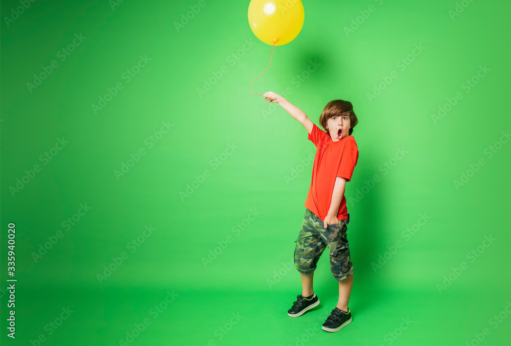 Fototapeta premium young boy holding a balloon with surprised expression