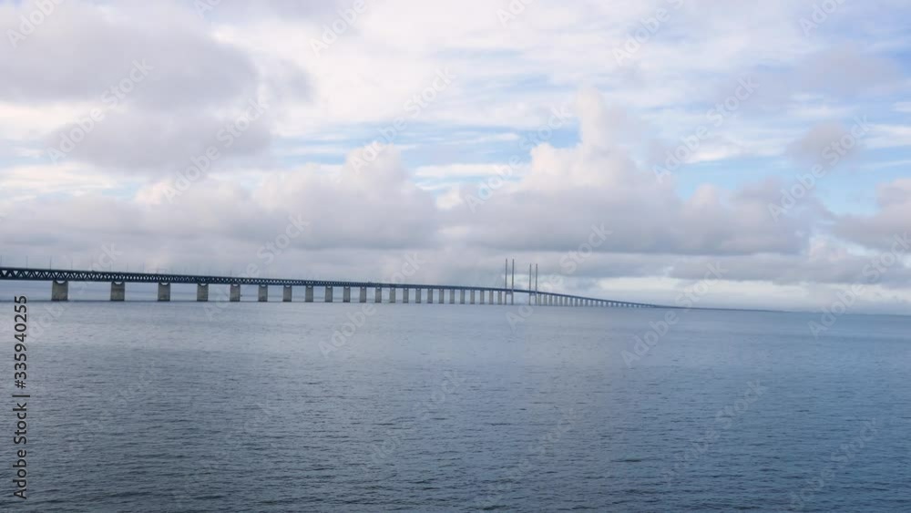 Long shot of Oresund Bridge over the sea, the borden between Sweden and Denmark with a cloudy blue sky in background Long shot of Oresund Bridge over the sea, the borden between Sweden and Denmark with a cloudy blue sky in background
