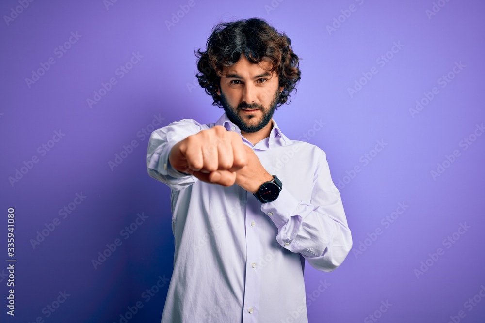Young handsome business man with beard wearing shirt standing over purple background Punching fist to fight, aggressive and angry attack, threat and violence Young handsome business man with beard wearing shirt standing over purple background Punching fist to fight, aggressive and angry attack, threat and violence