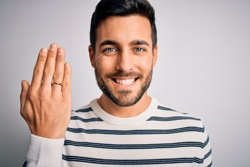 Handsome man with beard showing alliance ring marriage on finger over white background with a happy face standing and smiling with a confident smile showing teeth