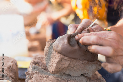 Hands of a person making a clay sculpture.