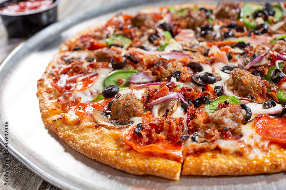 A view of a supreme pizza pie, in a restaurant or kitchen setting.