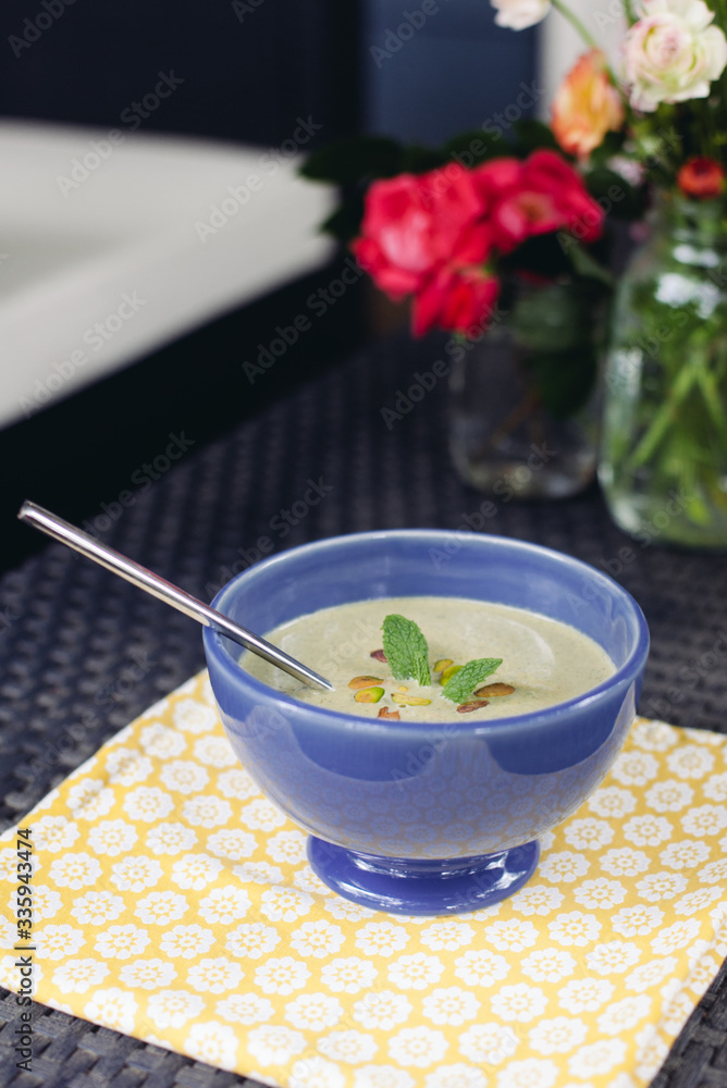 Pistachio cold soup garnished with mint in a blue bowl Pistachio cold soup garnished with mint in a blue bowl