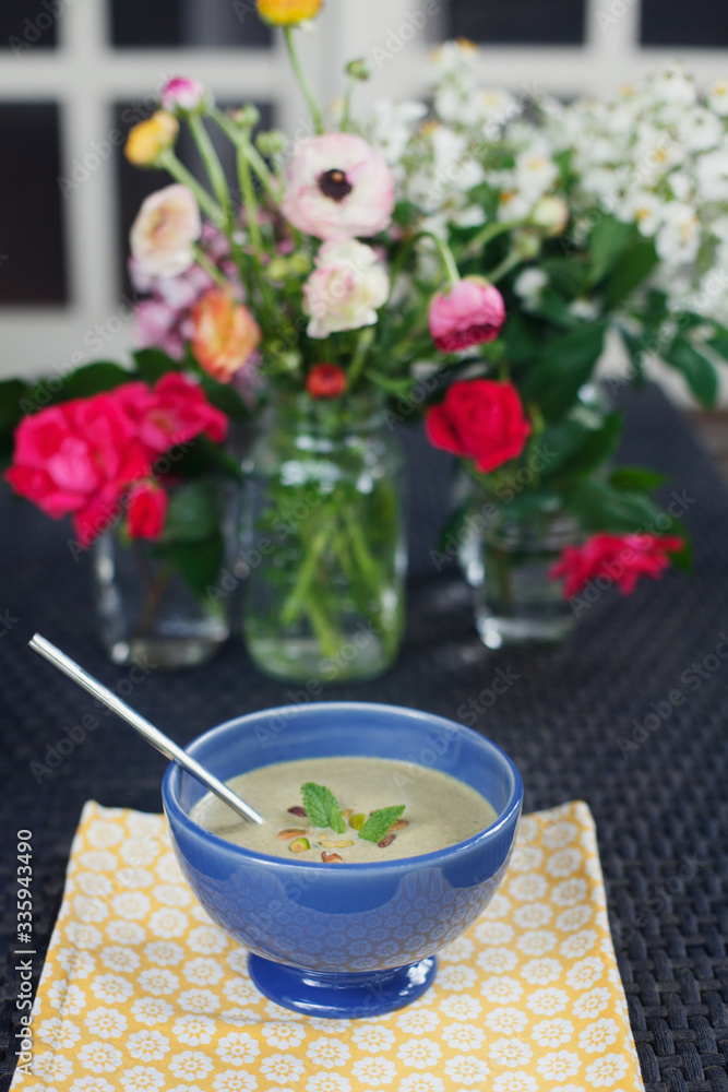 Pistachio cold soup garnished with mint in a blue bowl Pistachio cold soup garnished with mint in a blue bowl