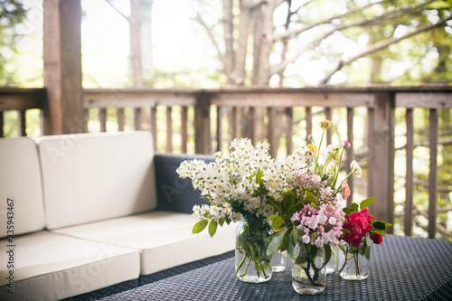 Freshly cut spring flowers in glass jars on a terrace outdoors