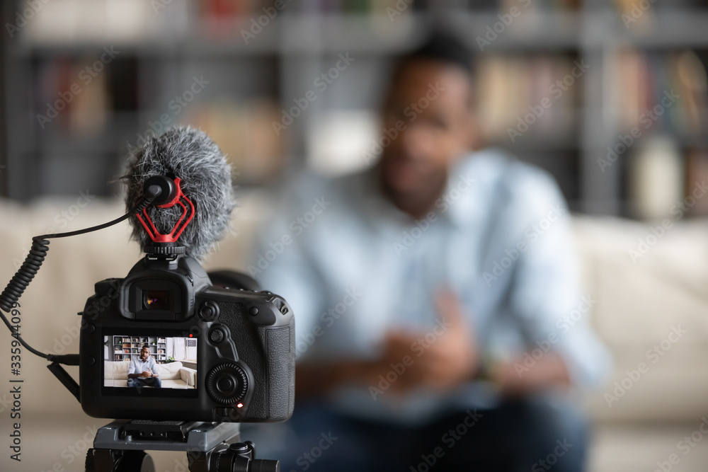 Close up focus of modern professional camera shooting african American male coach or tutor making vlog, biracial man blogger talk with subscribers record video tutorial on web cam, technology concept