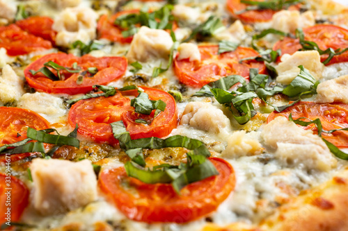 A closeup view of the texture of a Margherita and chicken pizza pie, as a background.
