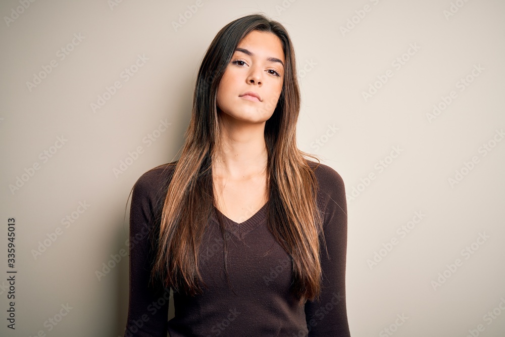 Young beautiful girl wearing casual sweater standing over isolated white background Relaxed with serious expression on face. Simple and natural looking at the camera. Young beautiful girl wearing casual sweater standing over isolated white background Relaxed with serious expression on face. Simple and natural looking at the camera.