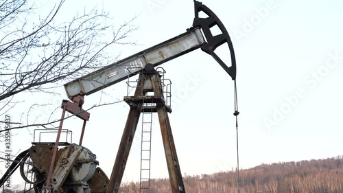 Industrial oil pump jack pumping crude oil for fossil fuel energy with drilling rig in oil field. photo