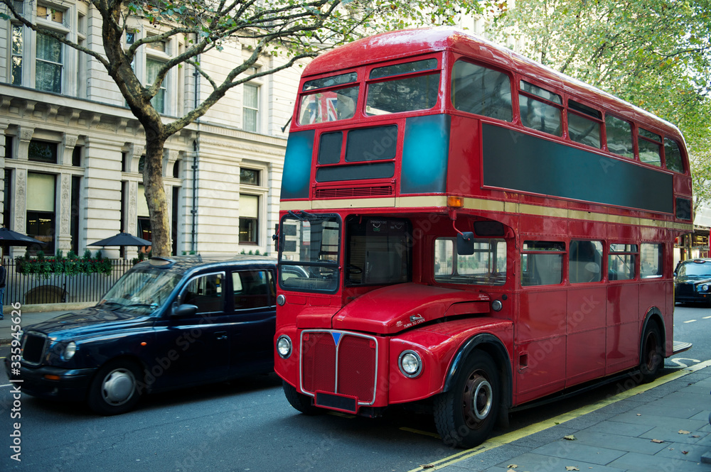 Traditional red double-decker Routemaster bus, introduced in 1956, making its way along an empty summer street in London, UK