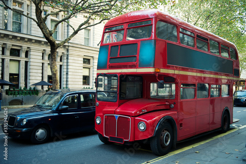 Traditional red double-decker Routemaster bus  introduced in 1956  making its way along an empty summer street in London  UK
