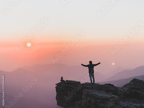 Man taking photo on sunset mountain peak. 