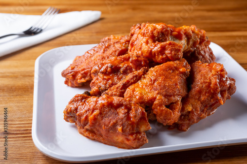 A closeup view of a plate of buffalo wings, in a restaurant or kitchen setting.