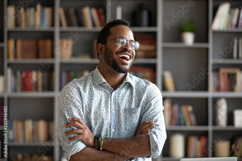 Overjoyed biracial young man in glasses stand laugh talking with friend or colleague, happy excited African American millennial male have fun engaged in pleasant conversation at home or workplace © fizkes